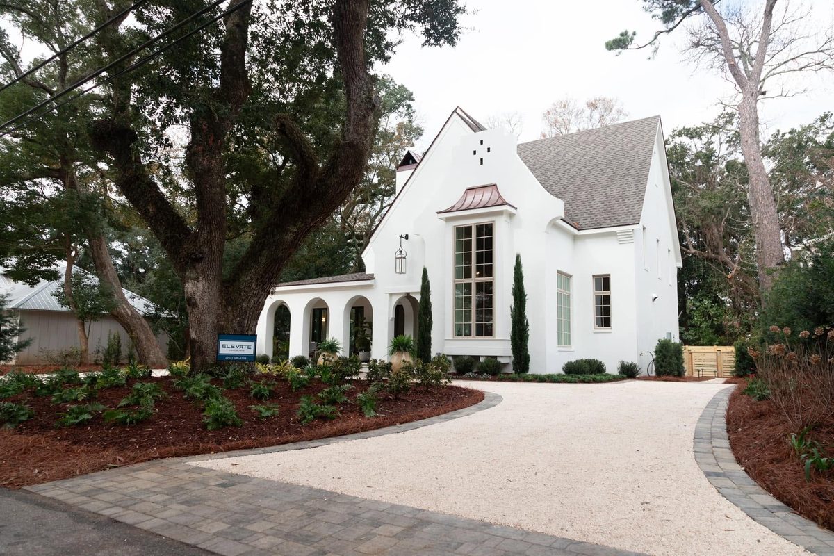White stucco home with a crushed-shell circular drive, fern beds and Italian cypress