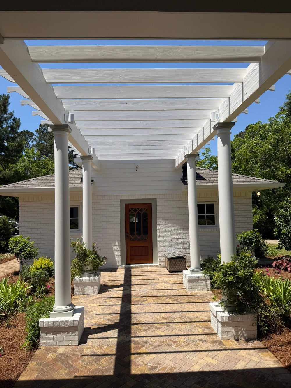 White pergola over a herringbone paver entry courtyard