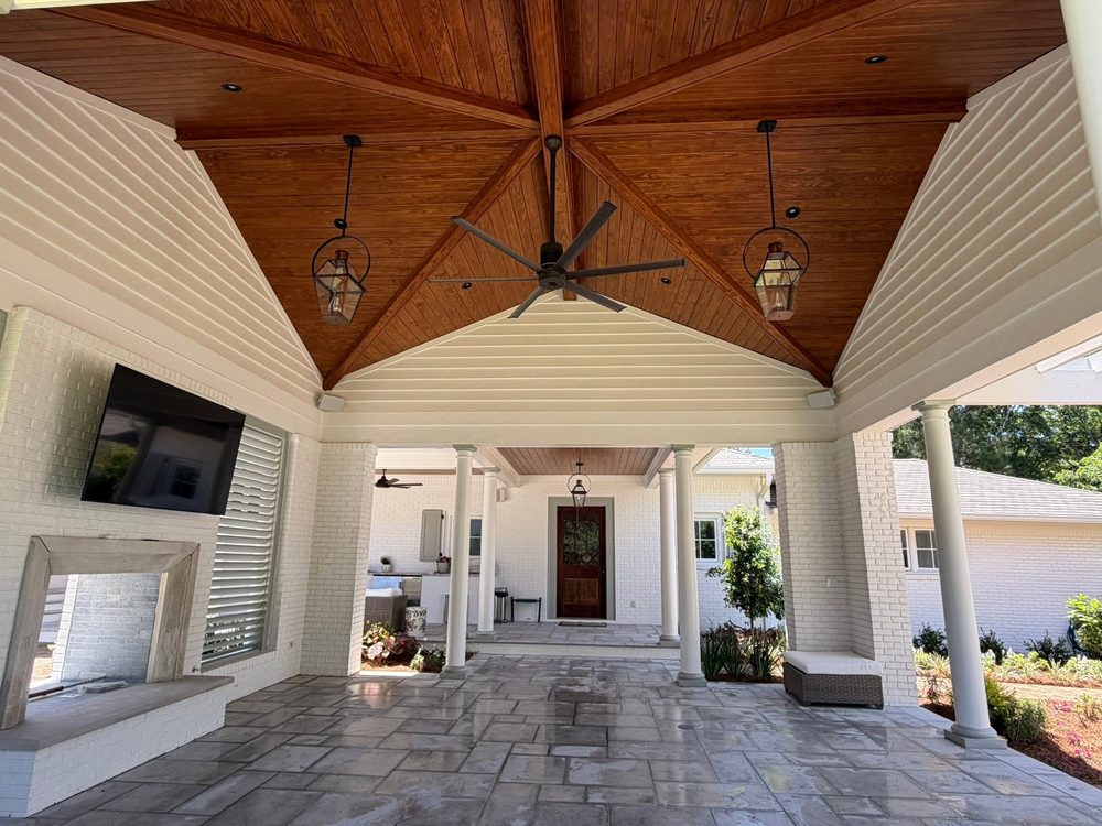 Covered outdoor living space with a stained wood ceiling and fireplace